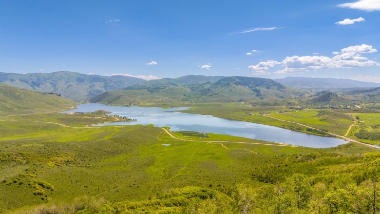 An aerial view of a reservoir surrounded by green hills and mountains. 