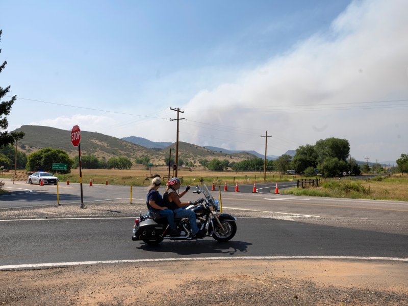 a pair of people on a motorcycle with smoke in background