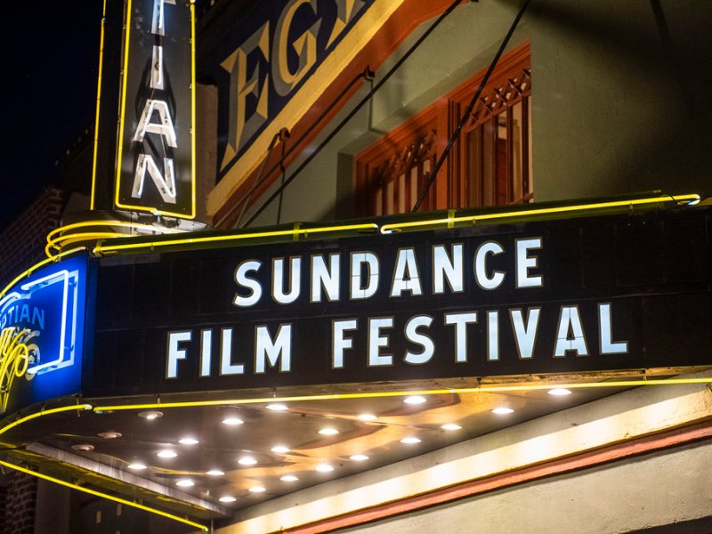 Marquee sign in front of a theater displaying "Sundance Film Festival" in large white letters, illuminated against a night sky.