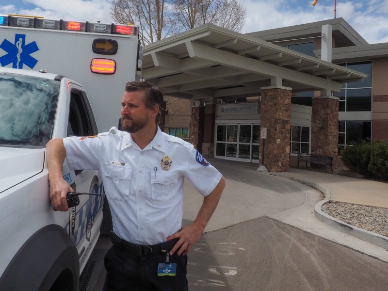 A paramedic in a white shirt stands near an ambulance outside Gunnison Valley Hospital