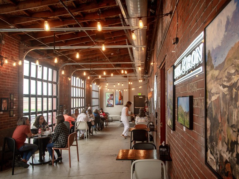 the interior of a food hall with people sitting at tables.