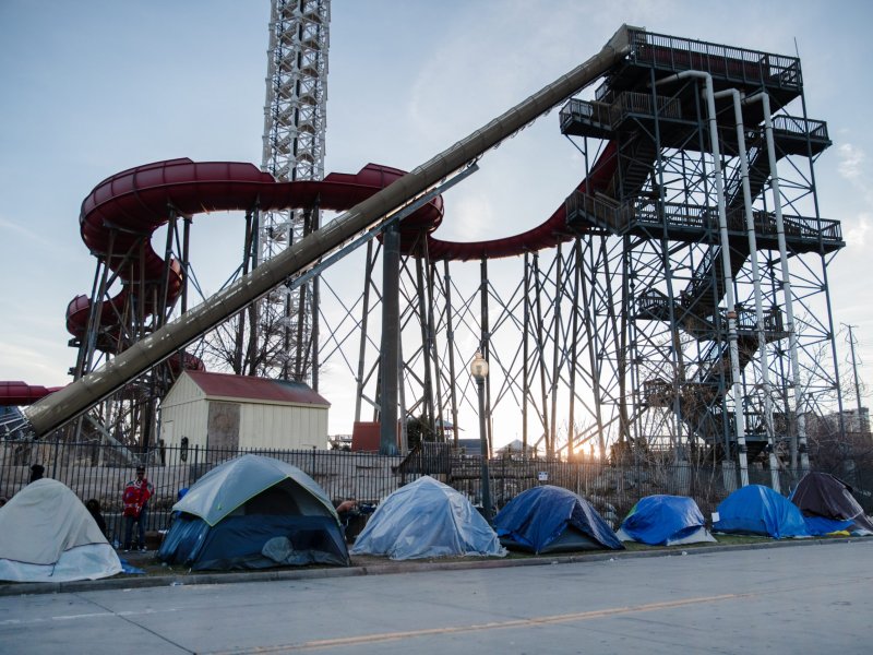 A group of tents line the sidewalk outside an amusement park