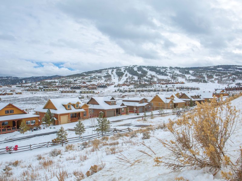 A group of houses in the snow with mountains in the background.