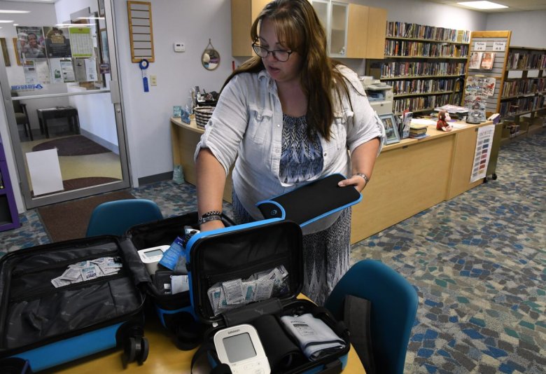 A person standing in a room with shelves, organizing medical equipment in bags on a table.