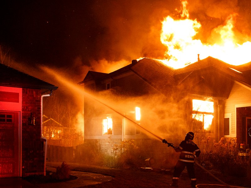 A firefighter tries to put out a house that's on fire