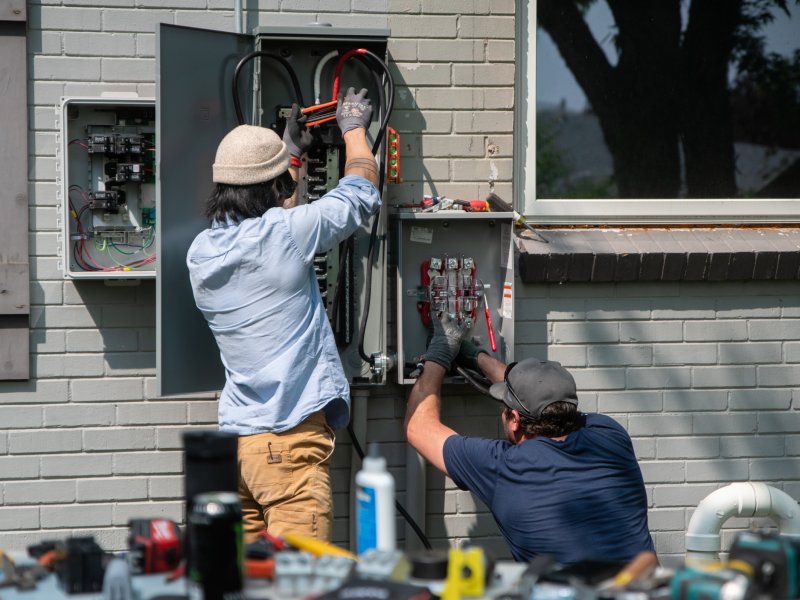 Two men working on an electrical panel.