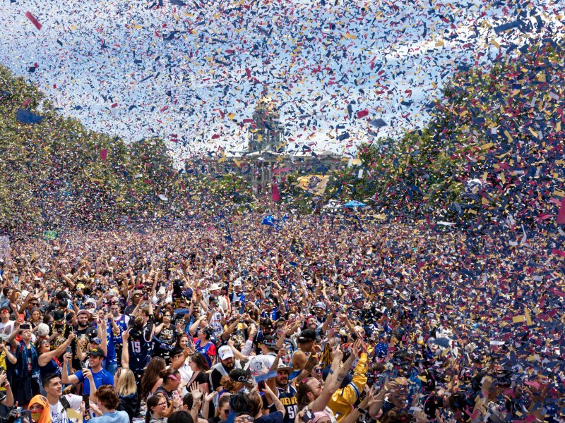 Confetti fills the air as a giant crowd of people fill a park with the Capitol building in the background