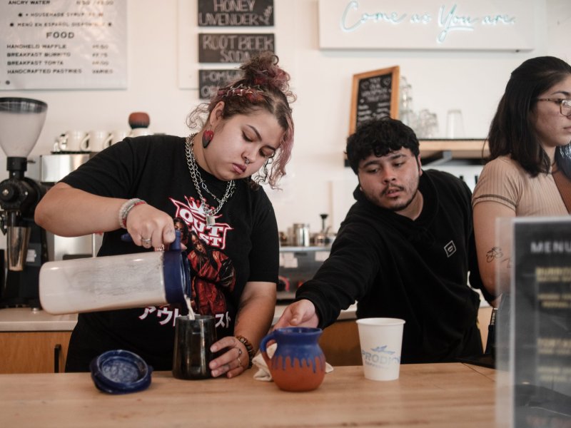 Young people make drinks behind a bar in a coffee shop