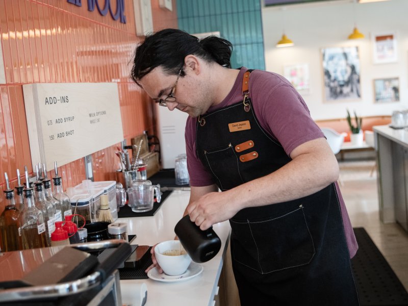 A man pours steamed milk into a latte