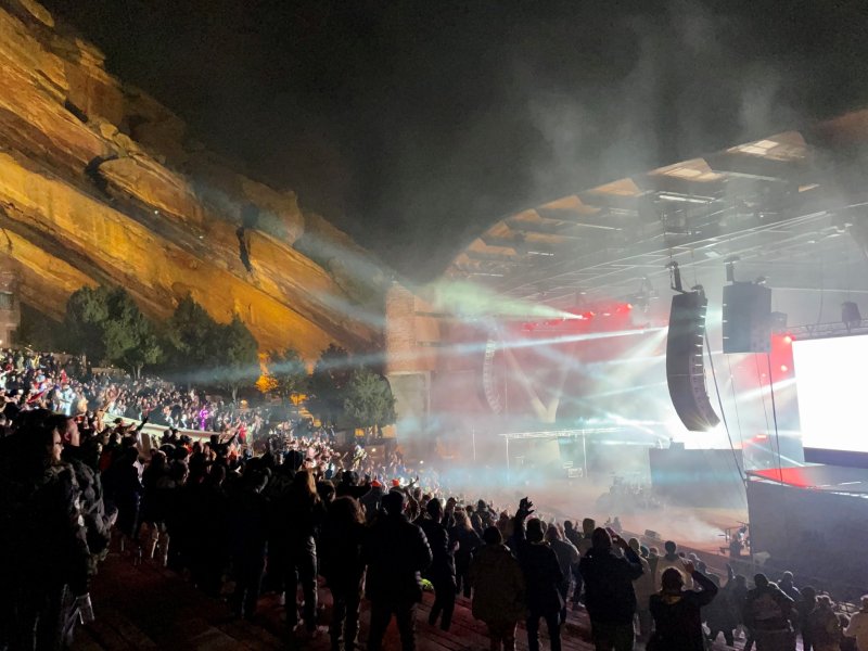 A crowd of people watching a concert at night at Red Rocks Amphitheatre.