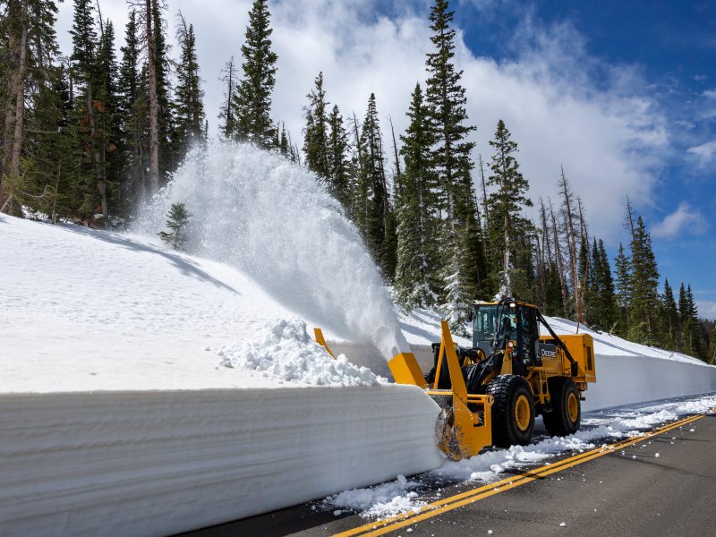 a snow plow clearing a road in the mountains.