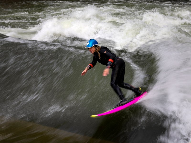 A motion blur of a whitewater river as a surfer rides a wave