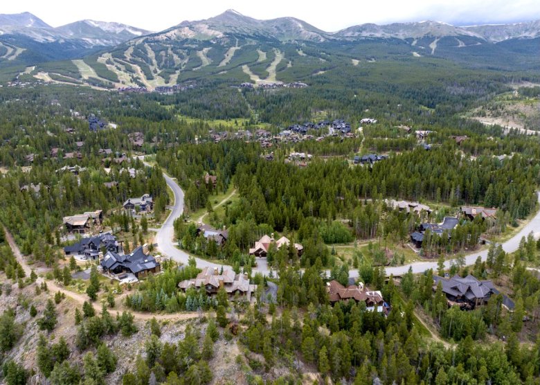 aerial view of large homes in a forest with mountain backdrop