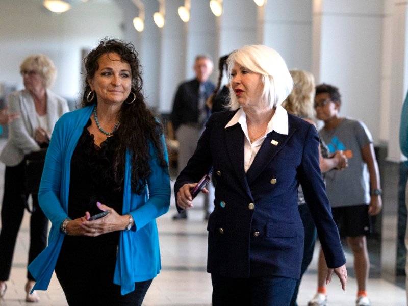 a pair of women in formal clothing walking indoors