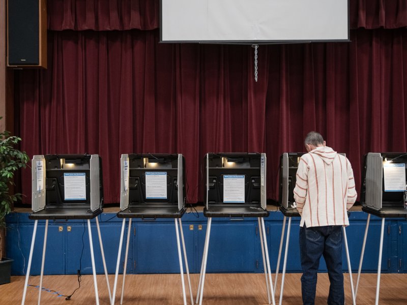 A person fills out a ballot while surrounded by empty polling stations