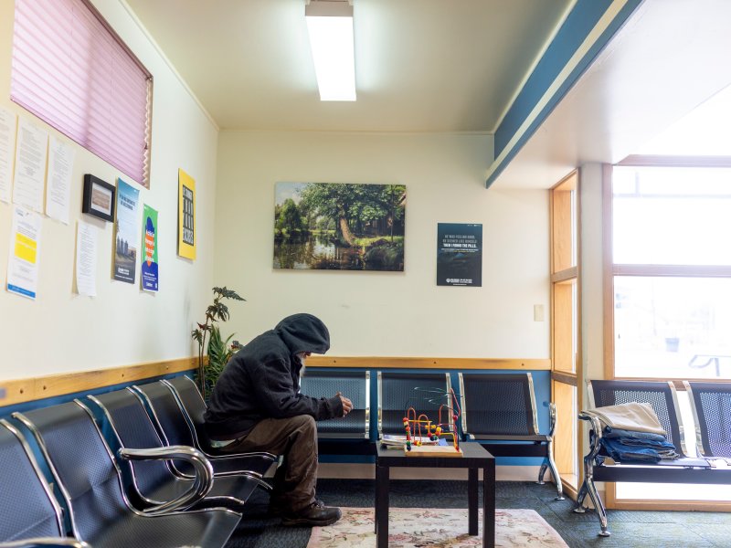 a lobby area filled with empty chairs but with one person slouched in a black hooded jacket