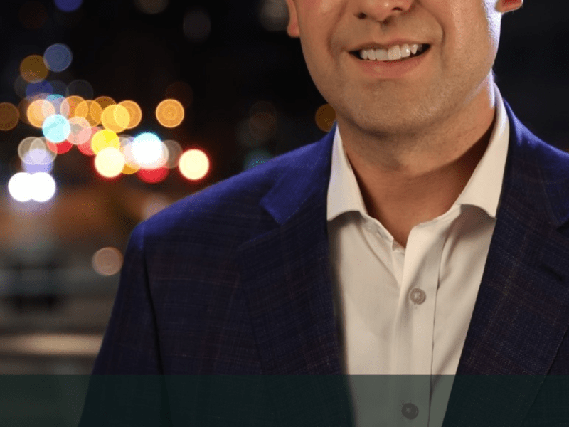 A person in a suit stands outdoors at night. The text on the image reads "KYLE CLARK, 9NEWS ANCHOR.